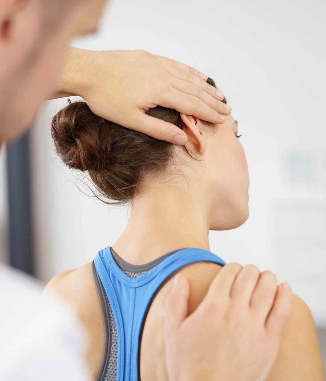 Orthopäde behandelt Patientin am Nacken.